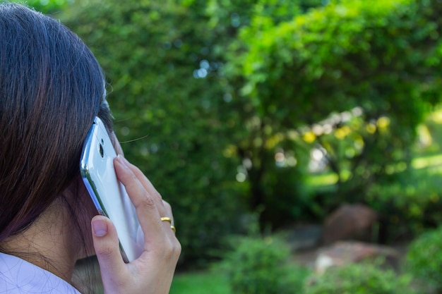 Closeup of female hands using a smart phone, green nature background