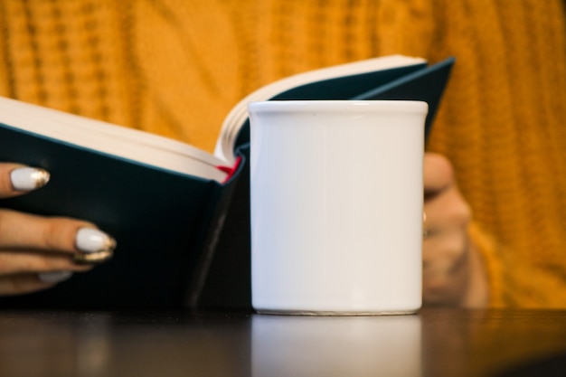 closeup of female hands with a mug of beverage beautiful woman in yell sweater holding cup of tea