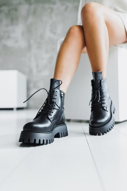 Closeup of female legs in black leather boots Women's winter shoes Warm women's boots Women's modern shoes