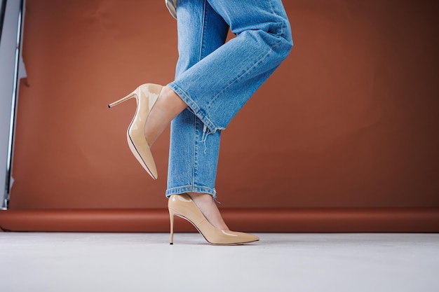 Closeup of female legs in blue jeans and fancy beige high heels Women's leather pumps