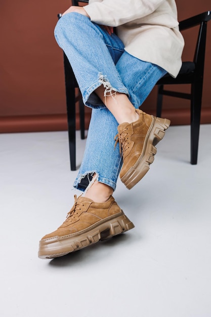 Closeup of female legs in blue jeans and suede brown sneakers Women's leather casual sneakers