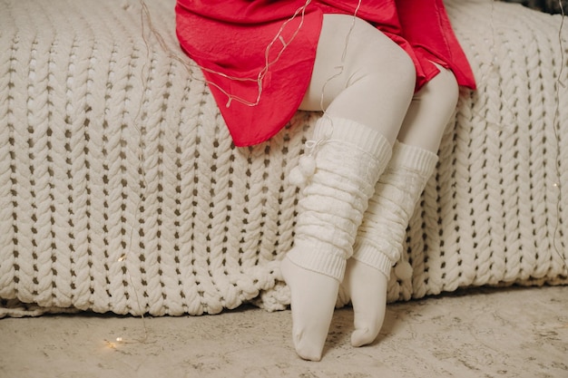 Closeup of female legs dressed in warm leggings sitting on the bed