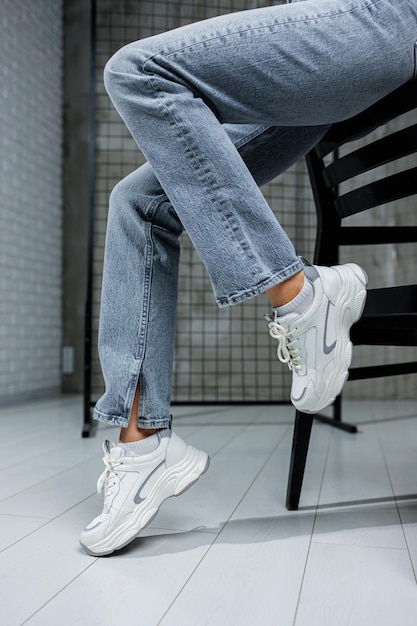 Closeup of female legs in jeans and shoes in fashionable sneakers closeup Women's everyday fashionable shoes