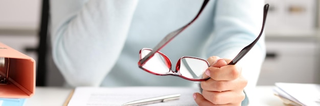 Closeup of female office manager working with documents at workplace woman holding glasses in