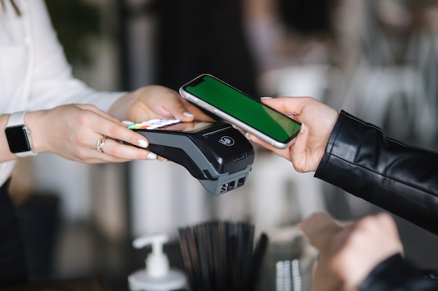 Closeup of female paying with smartphone