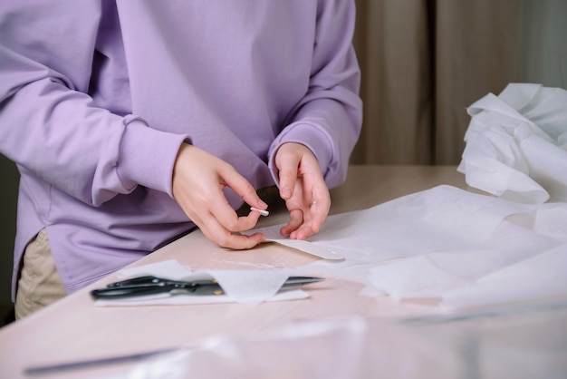 Closeup of female tailor working with paper sewing patterns in her workshop