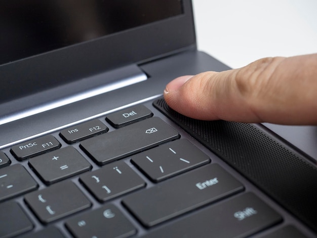 Closeup of a finger pressing the laptop power button Fingerprint scanner Modern devices for work and leisure selective focus