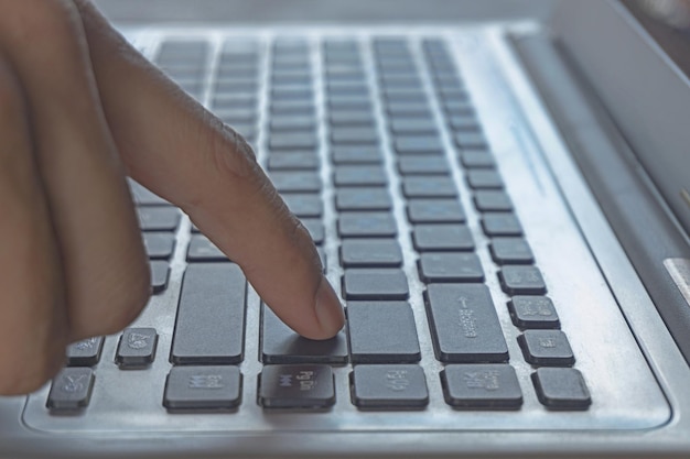 Closeup of fingers businessmans hand is using the Enter key of the computer notebook keyboard Concept of Laptop for freelance education business finance programmer working at the home office