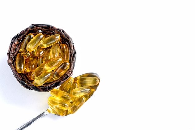 Closeup of fish oil capsules in a spoon and basket on a white background Omega 3 capsules natural vitamins