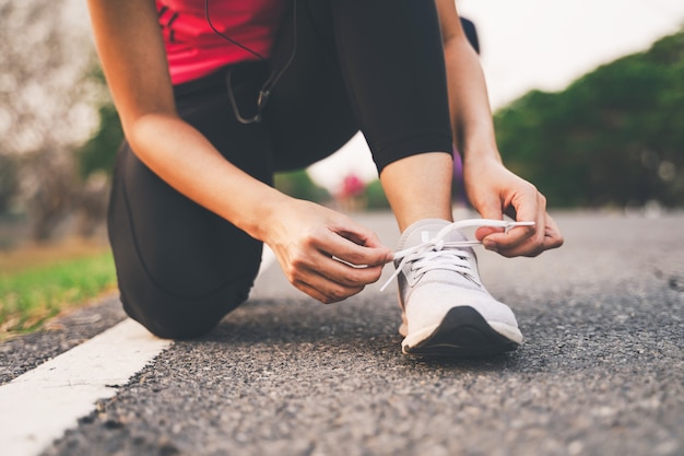 Closeup of fitness woman tying shoe laces in the park during sunset