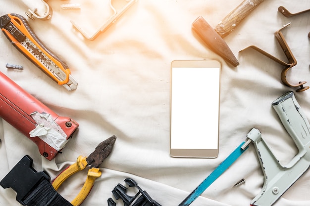 Closeup flat lay of tools on a wooden surface texture with smartphone blank screen