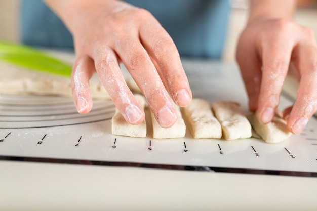 Closeup of floured hands spreading pieces of dough along the markings on a silicone baking mat