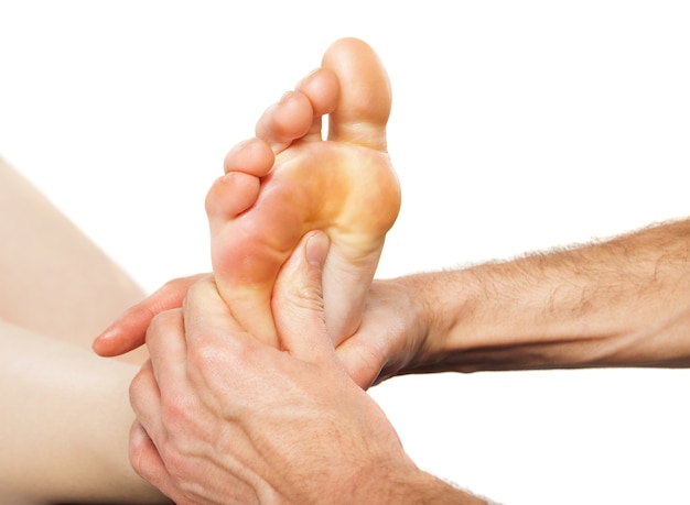 Closeup of foot receiving massage on white