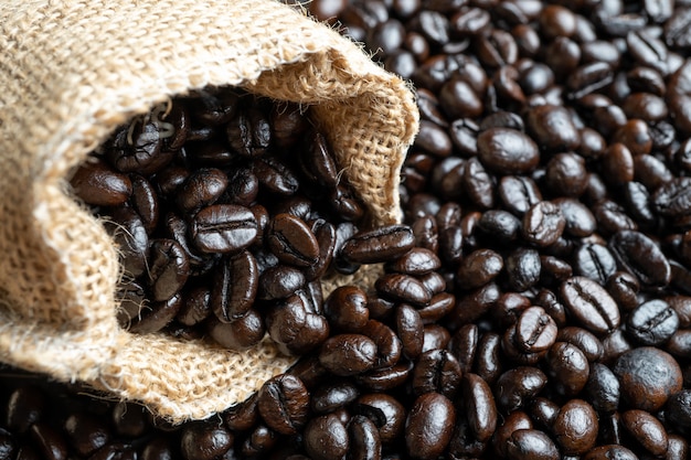 Closeup Fresh Coffee beans in bag made from burlap on wooden surface.