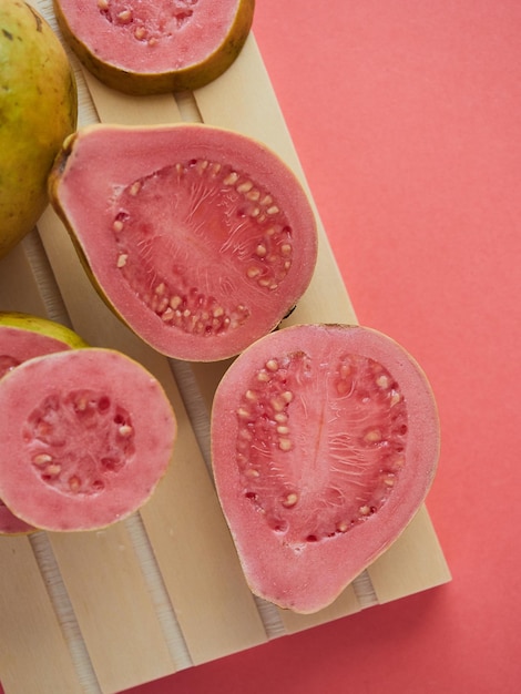 Closeup of a fresh guava cut in half the pink color of the pulp matches the background