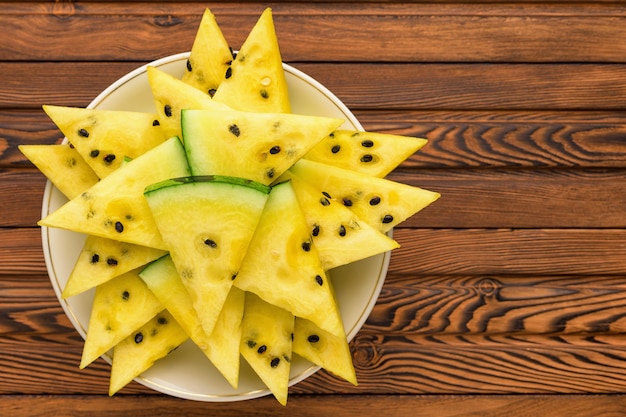 Closeup of fresh yellow watermelon slices on white plate