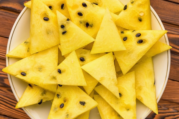 Closeup of fresh yellow watermelon slices on white plate