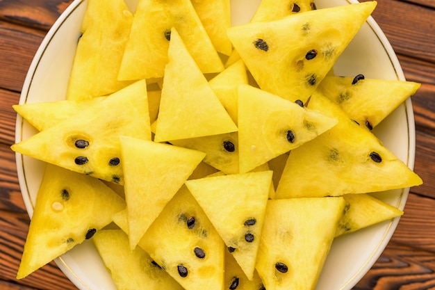 Closeup of fresh yellow watermelon slices on white plate