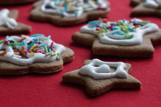 Photo closeup of ginger christmas biscuits with sugar icing on the red cloth