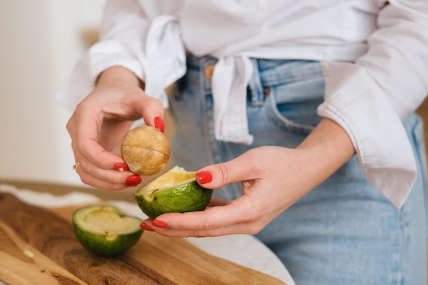 Closeup of a girl's hand holding an avocado cut in two