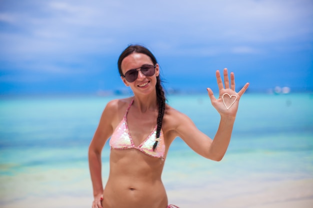 Closeup of girl's hand with heart on the palm painted by suncream