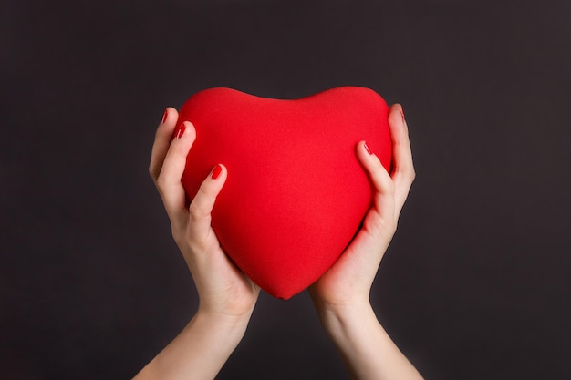 Closeup of girls hands holding big red heart