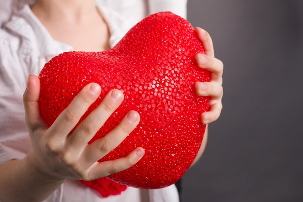 Closeup of girls hands holding big red heart