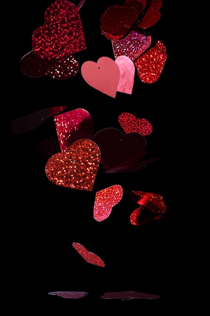 Closeup glittery, red cutout hearts against a black background - Valentine's theme background