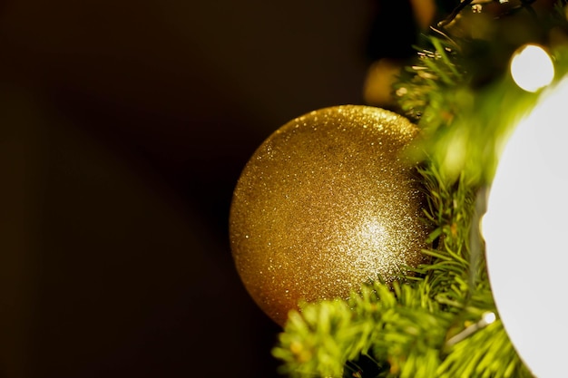 Closeup golden Christmas Balls Decorated on Pine Tree on Christmas night on black background