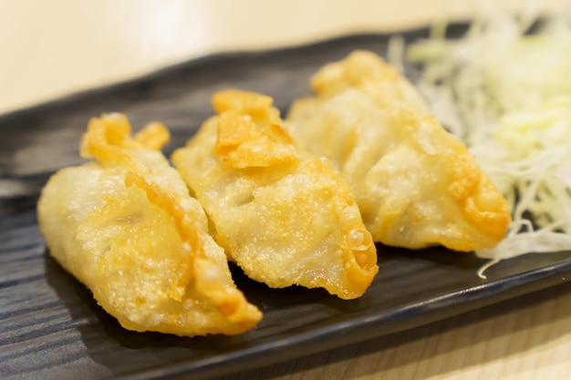 Closeup of golden yellow gyoza placed on black plate with blurred background