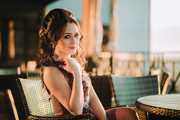 Closeup of gorgeous nice young woman sitting in street cafe and posing for camera