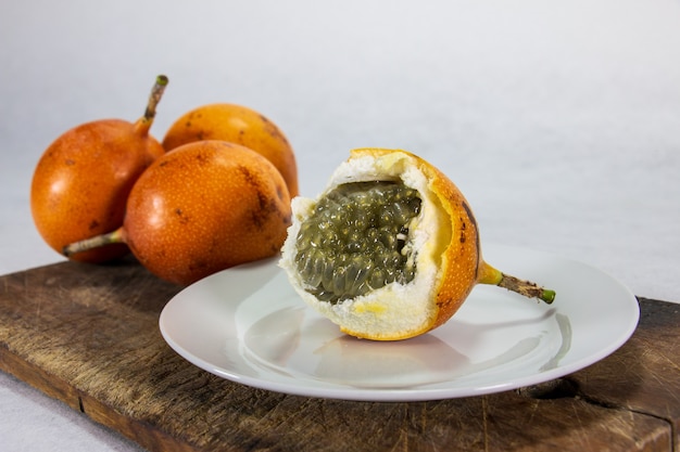 Photo closeup granadilla a hardskinned peruvian fruit on a porcelain plate and wooden board