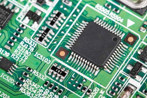 Closeup of a green computer printed circuit board with selective focus on a chip