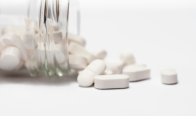 Closeup of a group white pills in crystal bottle.