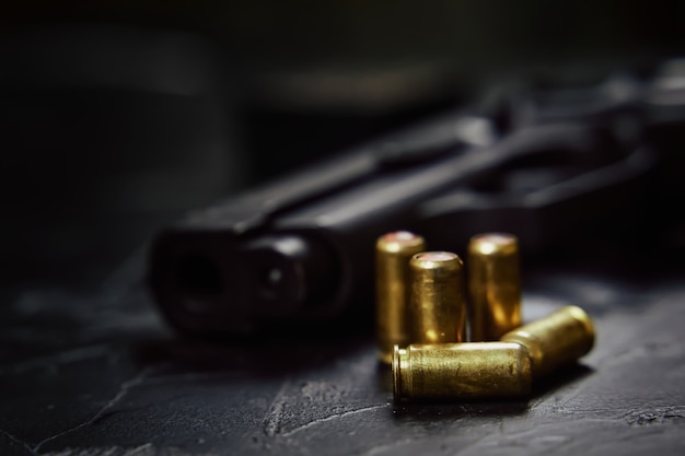 Closeup of gunpoint and bullets on concrete table pistol for defense or attack firearms and ammunition