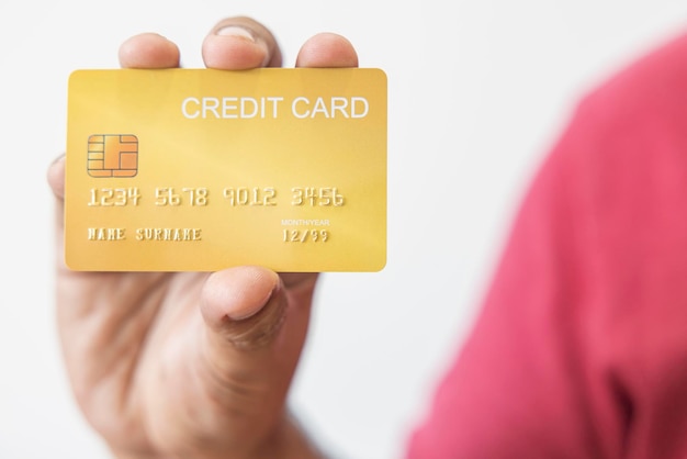 Closeup hand of Asian man holding yellow gold credit card in his hand isolated on white background Concept of finance trading communication social technology business