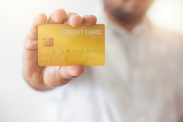 Closeup hand of Asian man holding yellow gold credit card in his hand isolated on white background Concept of finance trading communication social technology business