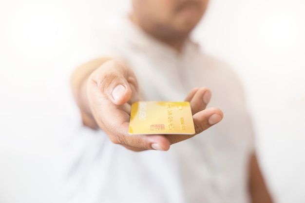 Closeup hand of Asian man holding yellow gold credit card in his hand isolated on white background Concept of finance trading communication social technology business