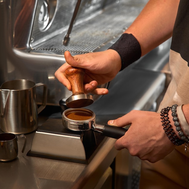 Closeup of hand Barista cafe making coffee with manual presses ground coffee using tamper