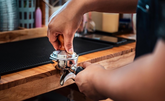 Closeup of hand Barista cafe making coffee with manual presses ground coffee using tamper