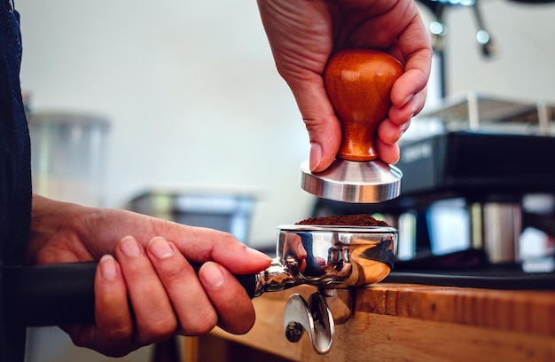 Closeup of hand Barista cafe making coffee with manual presses ground coffee using tamper