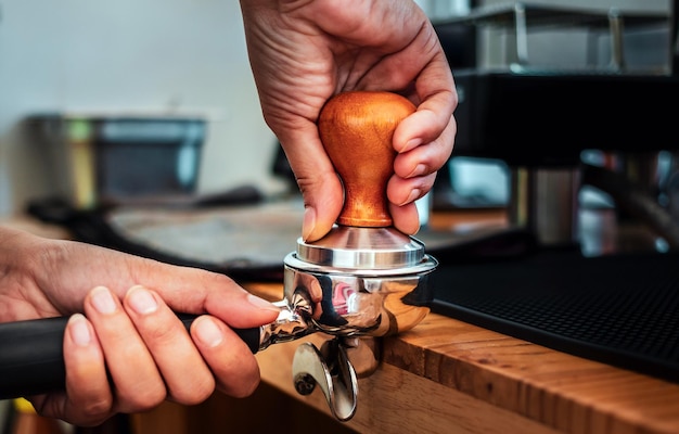 Closeup of hand Barista cafe making coffee with manual presses ground coffee using tamper