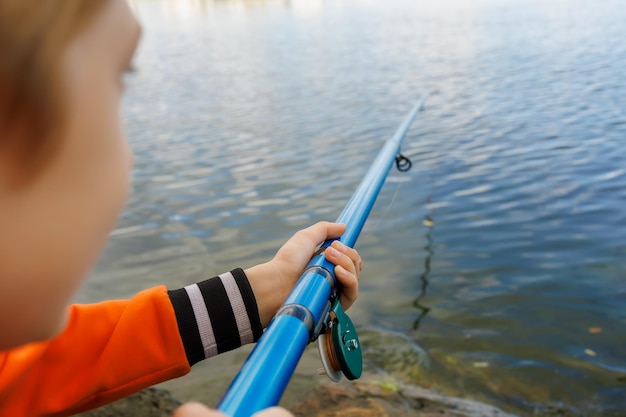 Closeup of the hand of a boy who holds a fishing rod and fishes