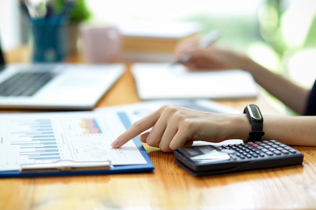 Closeup hand of businesswoman or accountant pointing index finger on financial spreadsheets, sale report, business paperwork at office