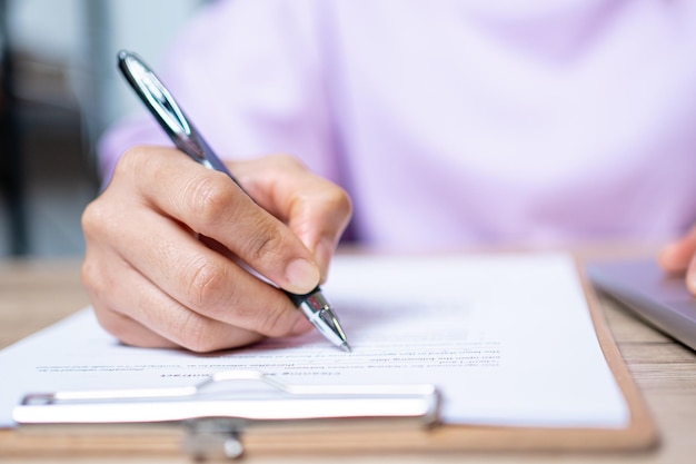 Closeup Hand of businesswoman writing signing documents on paper in office desk