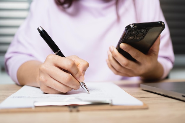 Closeup Hand of businesswoman writing signing documents on paper in office desk