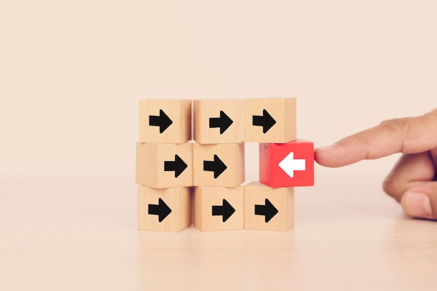 Closeup hand chooses arrow icon on cube wooden toy block stacked