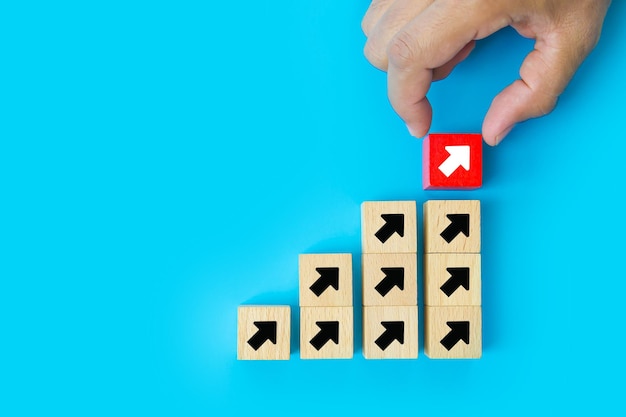 Closeup hand chooses wooden toy block with arrow icon pointing to opposite direction