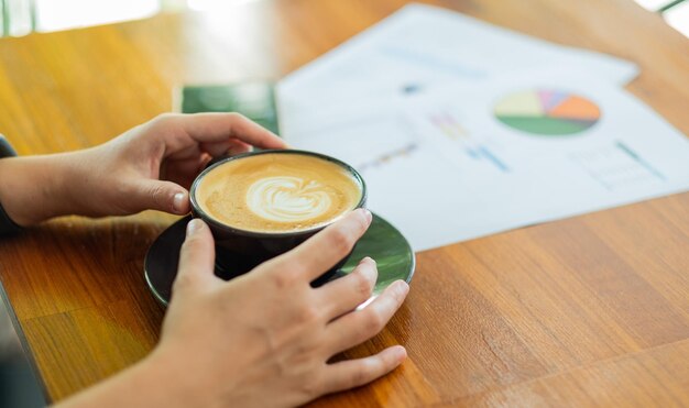 Closeup hand drinking hot coffee with working relax time