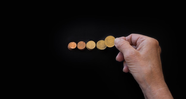 Closeup the hand of an elderly woman lays out coins on a black background